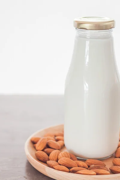 Nueces de almendra en plato de madera con leche — Foto de Stock