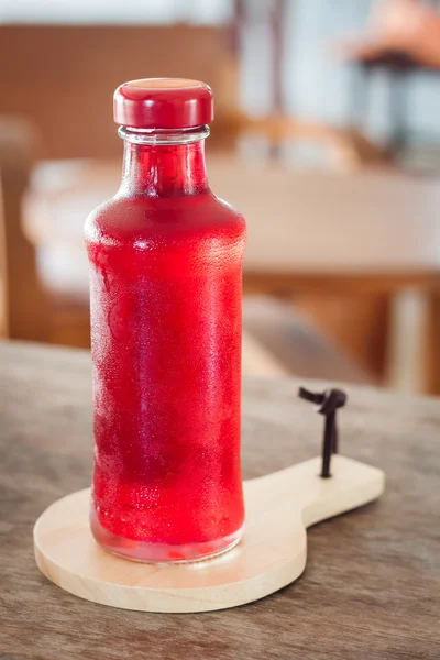 Red syrup in the bottle on wooden plate — Stock Photo, Image