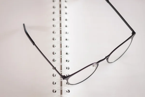 Eyeglasses on opened spiral notebook — Stock Photo, Image
