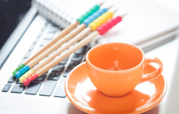 Laptop with coffee cup and notepad on desk