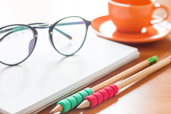 Crayons et lunettes sur carnet blanc vierge ouvert avec café — Photo