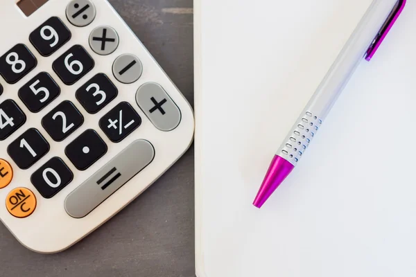 Calcolatrice, blocco note e penna su sfondo grigio — Foto Stock