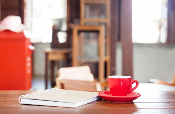 Xícara de café vermelho com notebook na mesa de madeira — Fotografia de Stock