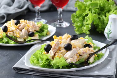 İki tabak ananaslı salata, fırında tavuk, mısır ve siyah zeytin ve iki kadeh kırmızı şarap.