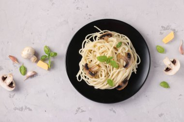 Mantarlı spagetti ve gri arka planda siyah tabakta fesleğen, Üst Manzara, Yatay Biçim