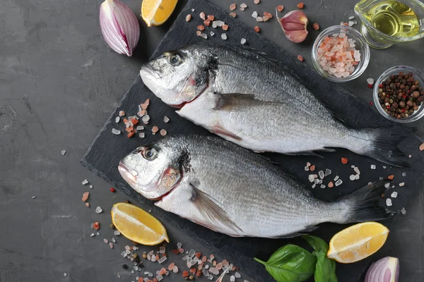 Fesleğen, limon, tuz, biber, kırmızı soğan ve zeytinyağı gibi malzemelerle çiğ balık dorado pişirmeye hazır. — Stok fotoğraf