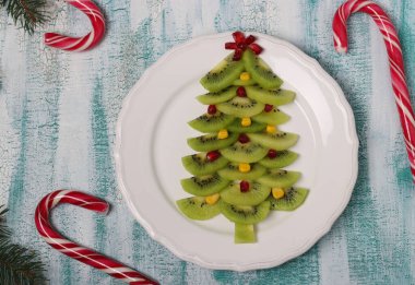 Kivi, mısır ve nar ağacından yapılmış Noel ağacı, Noel ve yeni yıl şenlik yemekleri için yaratıcı fikir, çocuklar için meyve atıştırmalığı. Üst görünüm