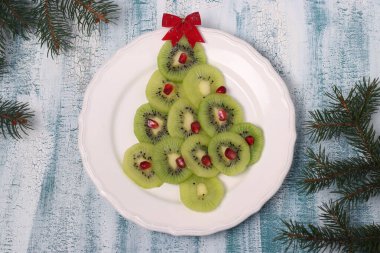 Kivi ve nar ağacından yapılmış Noel ağacı, Noel ve yeni yıl şenlik yemekleri için yaratıcı fikir, çocuklar için meyve atıştırmalığı.