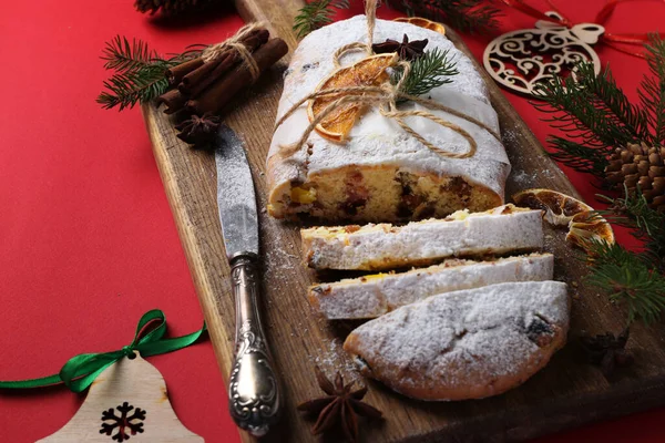 Christmas tasty stollen with dry fruits, berries and nuts on red background. Traditional German treats. — Stock Photo, Image