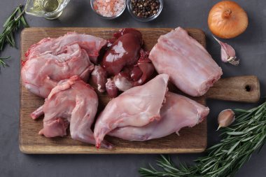 Tahtada doğranmış tavşan leşi ve pişirmek için taze malzemeler. Üst görünüm.