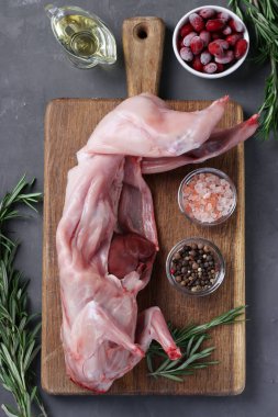 Taze çiğ tavşan zeytinyağı, biberiye, biber, deniz tuzu ve kornelian kirazları gri arka planda tahtada. Dikey format. Yukarıdan görüntüle.