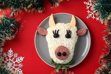 Kırmızı arka planda 2021 için şenlikli Boğa şekilli salata, yeni yıl için sembolik yiyecek. Yukarıdan bak. Yatay biçim