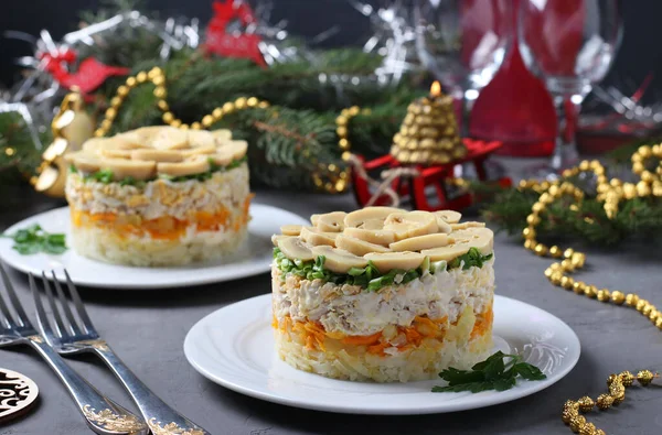 Puff salad with chicken, pickled mushrooms, potatoes and carrots on plates. New Year\'s composition.