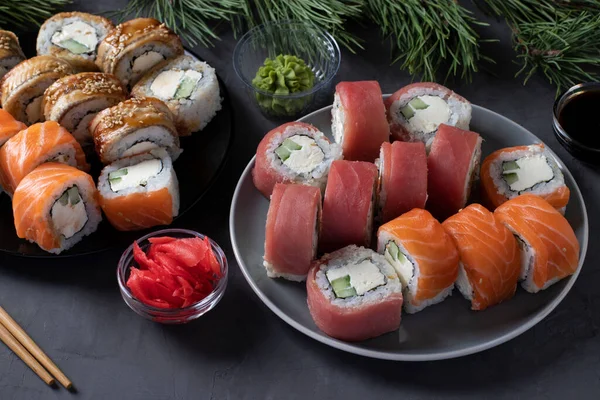 Świąteczna kolacja z łososiem, tuńczykiem i sushi z filadelfijskim serem. Przyjęcie noworoczne. Zbliżenie na ciemnym tle — Zdjęcie stockowe