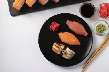 Suşi seti somon balıklı Asya yemeği, ton balığı ve beyaz arka planda Philadelphia peynirli yılan balığı. Soya sosu, wasabi, zencefil turşusu ve suşi için çubuklarla servis edilir. Üst görünüm