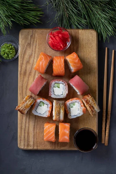 Zestaw sushi z łososia, tuńczyka i węgorza jako choinki służył na drewnianej desce jako ozdoba świąteczna na ciemnym tle. Widok z góry — Zdjęcie stockowe