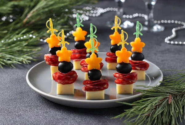 Canapes with cheese, sausage and black olives on a gray plate. Horizontal format — Stock Photo, Image