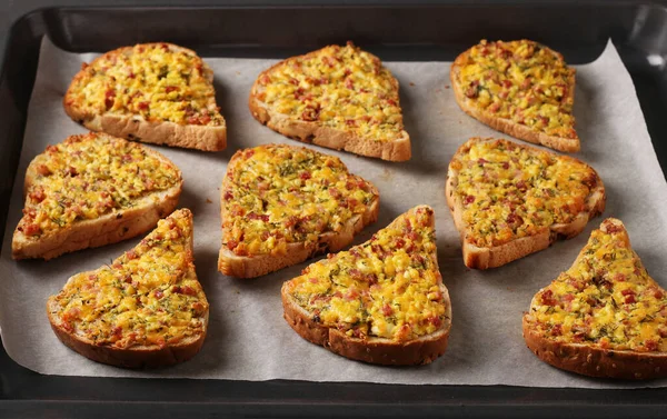 Sandvișuri calde de casă cu brânză și cârnați, pe pergament pe o tavă de copt, format orizontal, closeup — Fotografie, imagine de stoc