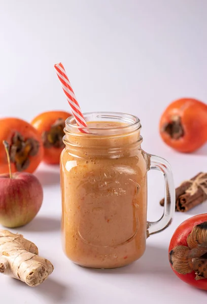 Hausgemachter Smoothie aus Kaki, Äpfeln, Ingwer und Zimt zur Erhöhung der Immunität im Glas auf weißem Hintergrund, vertikales Format. Nahaufnahme — Stockfoto