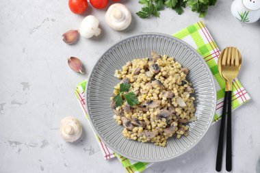 Açık gri masadaki bir tabakta şampiyonlarla ev yapımı ptitim makarna. Yatay format. Yukarıdan görüntüle
