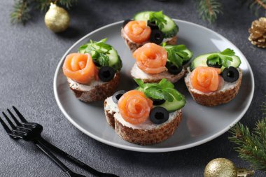 Somonlu sandviç, salatalık, krem peynir ve gri arka planda siyah zeytin. Ev yapımı tatil atıştırmalığı.
