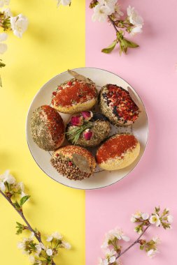 Farklı baharat ve mısır gevreğiyle süslenmiş pembe ve sarı arka planda koruyucular olmayan paskalya konsepti. Dikey format. Üst görünüm