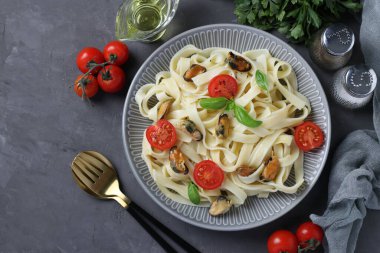 Tagliatelle makarnası, midye ve kiraz domatesli gri tabakta. Uzayı kopyala Flatlay biçimi.