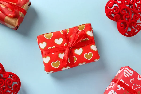 Paket kağıdında açık mavi arka planda kırmızı kurdeleli hediyeler. Sevgililer Günü konsepti. Yukarıdan görüntüle. — Stok fotoğraf