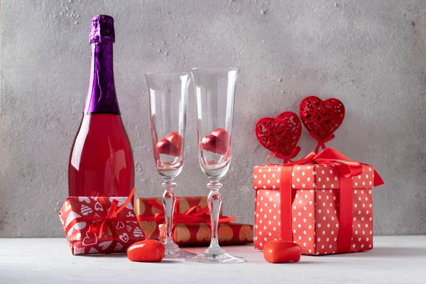 情人节快乐的概念 浪漫的晚餐 一瓶粉红色的香槟 心形糖果和浅灰背景的礼物 — 图库照片