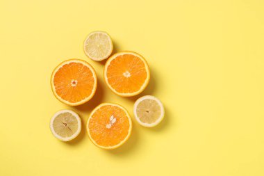 Yarım limon ve portakalların minimalizm tarzında kompozisyonu sarı zemin üzerinde metin için boşluk, yukarıdan görünüm