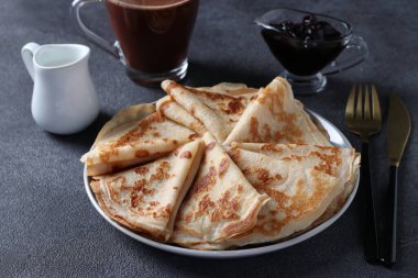 Buğday unu, yumurta ve yoğurtlu, böğürtlen reçeli, süt ve bir fincan kahveyle servis edilen bol ev yapımı krepler. Yakın çekim.