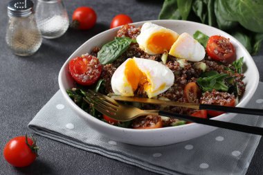 Kinoalı salata, ıspanak, haşlanmış yumurta ve gri arka planda vişneli domates. Sağlıklı beslenme. Kapat.