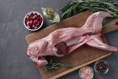 Taze çiğ tavşan zeytinyağı, biberiye, biber, deniz tuzu ve kornelian kirazları gri arka planda tahtada. Üst görünüm