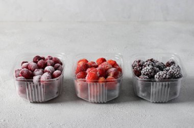 Donmuş böğürtlenli kaplar: açık gri arka planda böğürtlen, çilek ve kiraz. Kış için böğürtlen topluyorum..