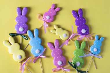 Sarı arka planda şirin tavşanlar şeklinde Paskalya renkli zencefilli ekmek. Paskalya konsepti. Yukarıdan görüntüle