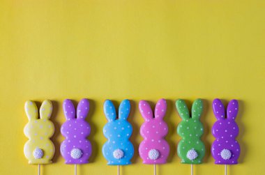 Sarı arka planda şirin tavşanlar şeklinde Paskalya renkli zencefilli ekmek. Paskalya konsepti. Yukarıdan görüntüle