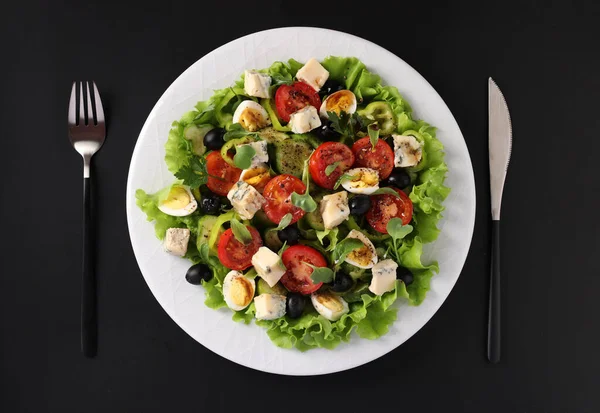 Zdrowa sałatka z pomidorów wiśniowych, ogórków, papryki, czarnych oliwek, przepiórek i sera gorgonzolla na czarnym tle, widok z góry — Zdjęcie stockowe