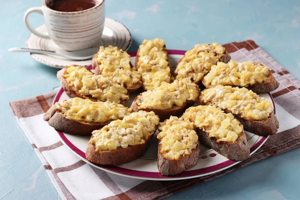 Toasturi de casă coapte cu pui, brânză, ananas și usturoi, precum și o ceașcă de cafea pe un fundal albastru deschis . — Fotografie, imagine de stoc