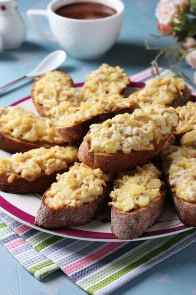Bakade hembakade rostat bröd med kyckling, ost, ananas och vitlök samt kopp kaffe på en ljusblå bakgrund. — Stockfoto
