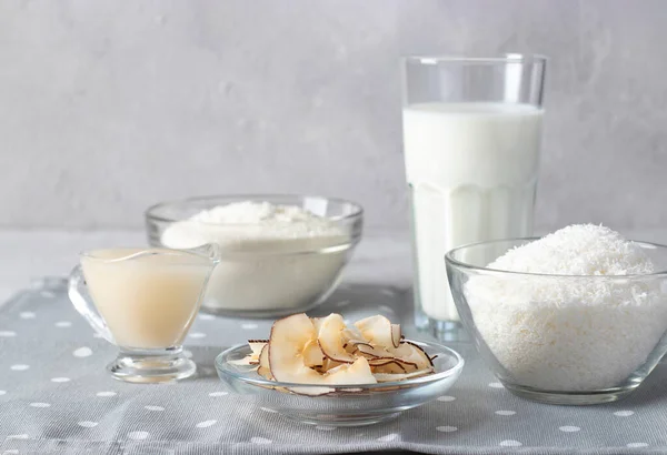 Prodotti a base di cocco: fiocchi di cocco, farina, latte, latte condensato e patatine su fondo grigio. Note di alimentazione — Foto Stock