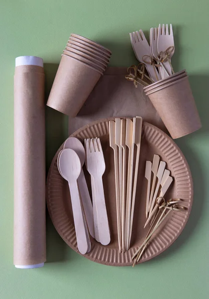 Disposable biodegradable tableware on craft paper plate - forks, spoons, glasses, bamboo skewers and parchment. Zero Waste. Vertical format