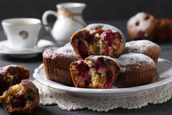 Muffins cu cireșe presărate cu zahăr pudră pe o placă albă pe un fundal întunecat. Close-up . — Fotografie, imagine de stoc