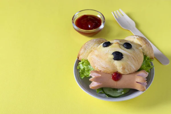 Sandviș pentru copii în formă de câine, constând dintr-un chifle, salată și cârnați, pe un fundal galben, cu un loc pentru text. Closeup — Fotografie, imagine de stoc