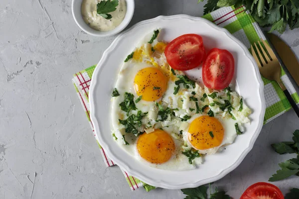 Œufs frits au céleri et au persil sur une assiette blanche, servis avec des tomates. Petit déjeuner sain et savoureux. Vue de dessus. Espace de copie — Photo