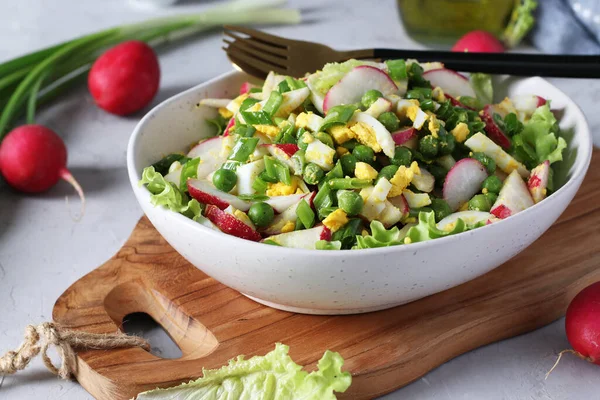 Salad with radishes, green onions, eggs and peas, seasoned with olive oil . Healthy food — Stock Photo, Image