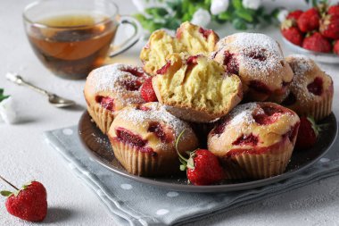 Açık gri arka planda ev yapımı çilekli kekler üzerine pudra şekeri serpiştirilmiş. Yakın plan.