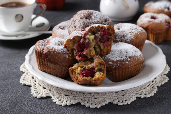 Muffinki z wiśniami posypane cukrem pudrem na białym talerzu na ciemnym tle. — Zdjęcie stockowe