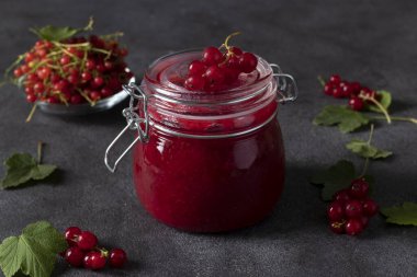 Koyu arkaplanda ev yapımı kırmızı frenk üzümü reçeli kavanozu. Yakın plan. Yatay biçim