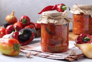 Patlıcanlı sebze salatası, havuç, biber, soğan ve domatesler cam kavanozlarda. Yatay biçim.