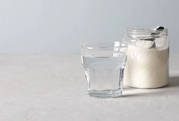 Glas av vatten, kollagen pulver i burk med mätsked på ljusblå bakgrund med plats för text — Stockfoto